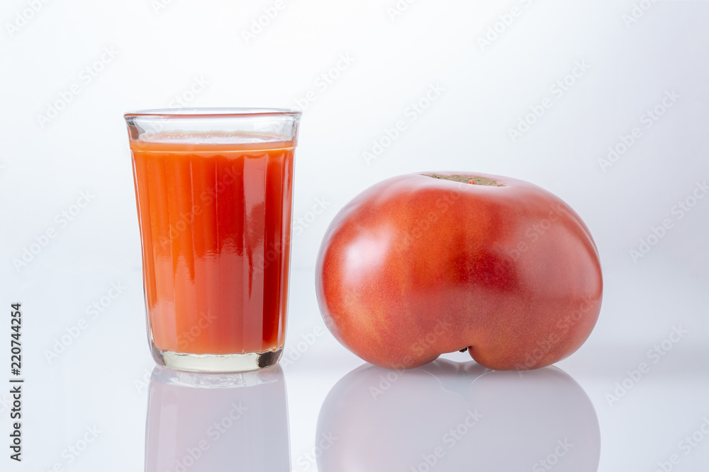 Large tomato and a glass of tomato juice Large tomato and a glass of tomato juice