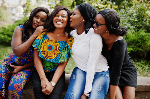 Group of four african american girls sitting outdoor and having fun.