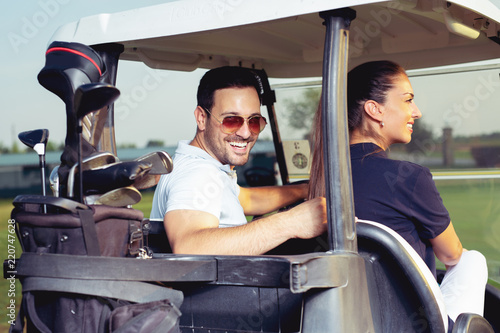 Couple smiling and driving in buggy in golf course