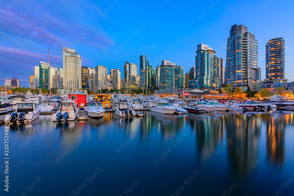 Sunset at Coal Harbour in Vancouver British Columbia with downtown buildings boats and reflections in the water