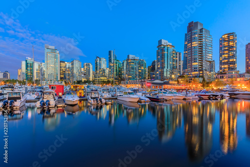 Sunset at Coal Harbour in Vancouver British Columbia with downtown buildings boats and reflections in the water