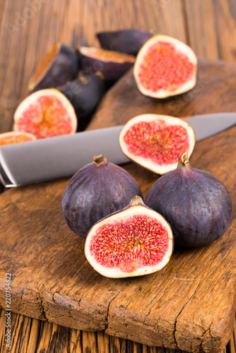 Group of whole and sliced ripe, delicious and sweets figs with a kitchen knife on a old rustic wooden cutting board