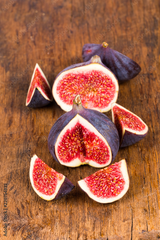 Group of sliced ripe, delicious and sweets figs on a old rustic wooden cutting board Group of sliced ripe, delicious and sweets figs on a old rustic wooden cutting board
