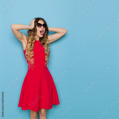 Bautiful Woman In Red Dress And Sunglasses Is Holding Head In Hands And Shouting