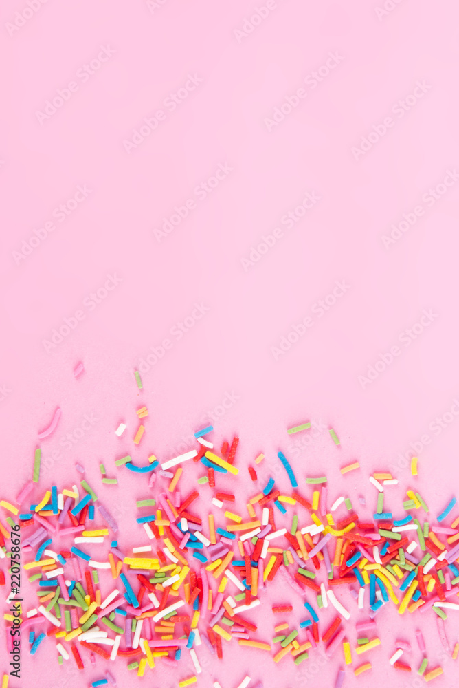 Fototapeta premium Sugar sprinkle dots hearts, decoration for cake and bakery, as a background. Isolated on pink.