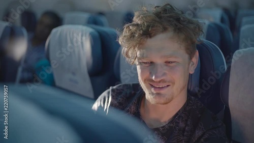 View across seats of caucasian man sitting in an airplane and watch a movie