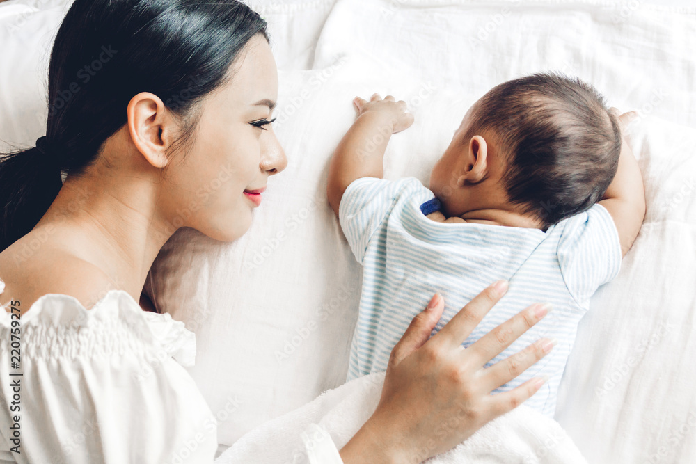 Mother holding sleeping baby on white bed.Love of family concept Mother holding sleeping baby on white bed.Love of family concept