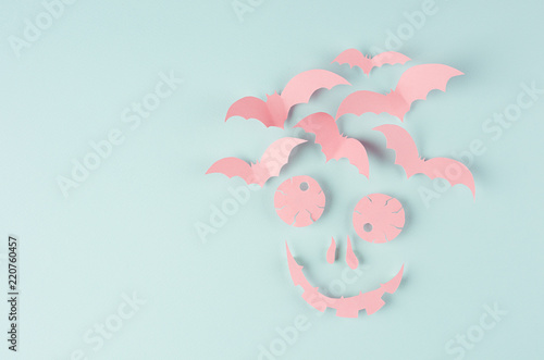 Terrible scary pink face with bats of cut paper on soft light pastel mint backround. Funny halloween modern concept art backdrop.