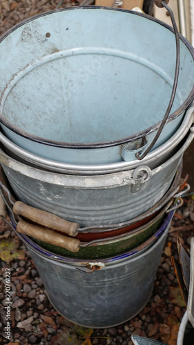 Stack of vintage metal buckets on a market stall, with enamel paint and wooden handles