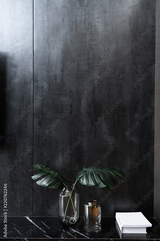 Living room corner in modern industrial style with artificial plants in glass  vase an empty book setting on natural black marble cabinet with weathered  black metal wall /cozy interior concept Stock Photo