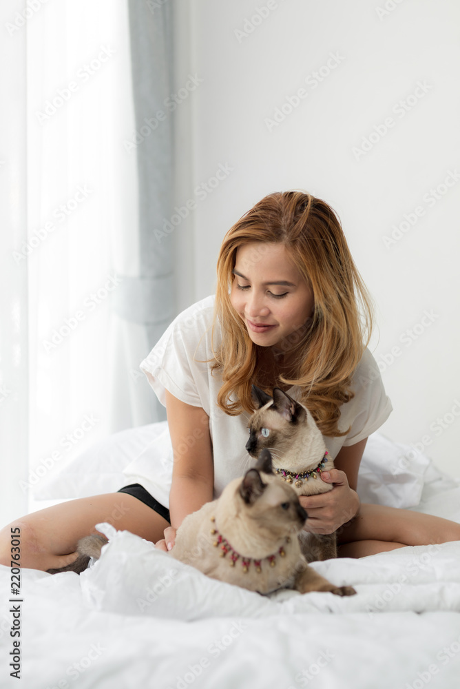 Happy Asian woman and her cats on bed. Happy Asian woman and her cats on bed.