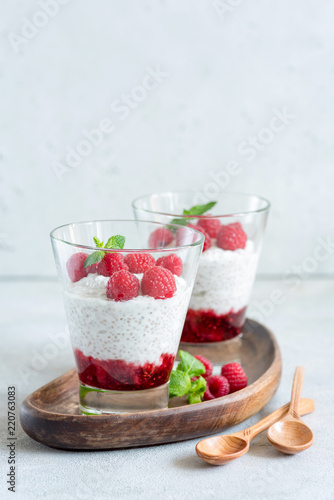 Chia pudding with raspberries in a glass on wooden serving board. Copy space for text. Concept of healthy lifestyle, healthy eating, vegan and vegetarian diet