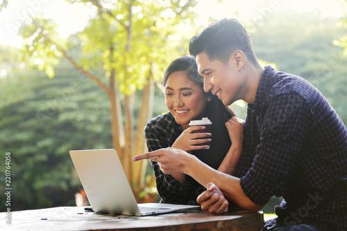 Happy asian couple looking at something on a laptop