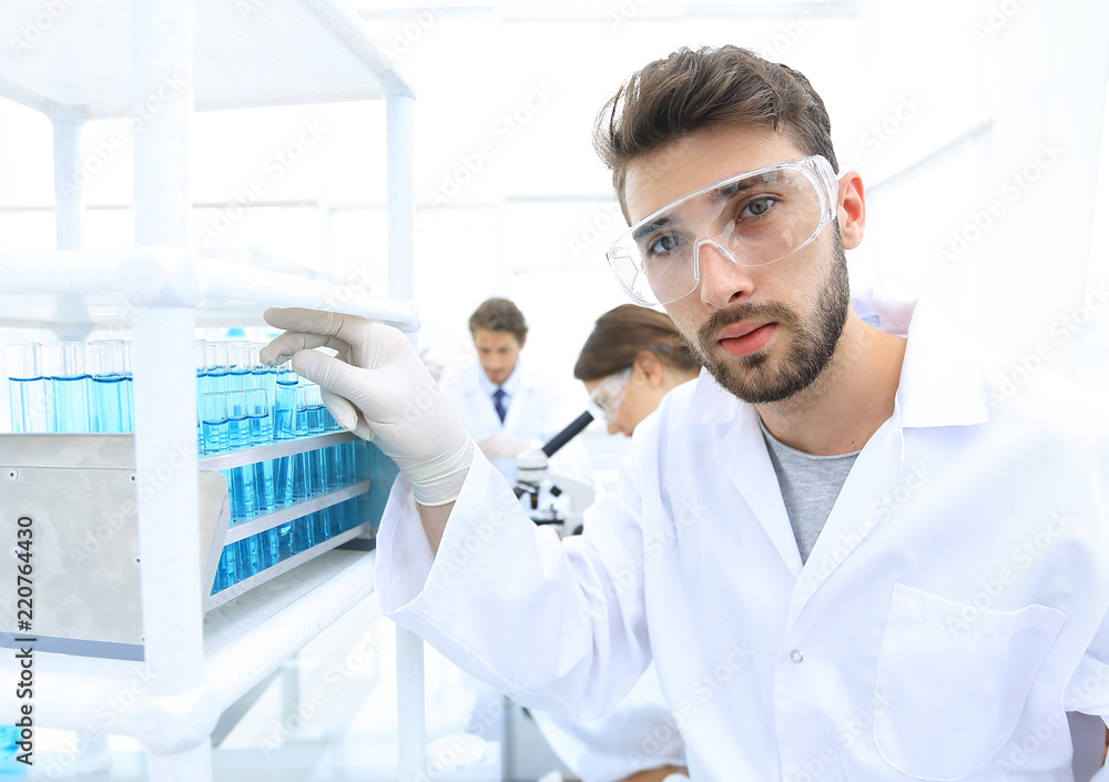 Young male scientist looking at a sample in a test tube side vie Young male scientist looking at a sample in a test tube side vie