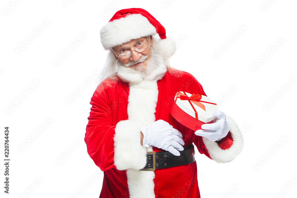 Christmas. Smiling Santa Claus in white gloves holds a red and white heart-shaped gift box with a red ribbon. Isolated on white background. Christmas. Smiling Santa Claus in white gloves holds a red and white heart-shaped gift box with a red ribbon. Isolated on white background.