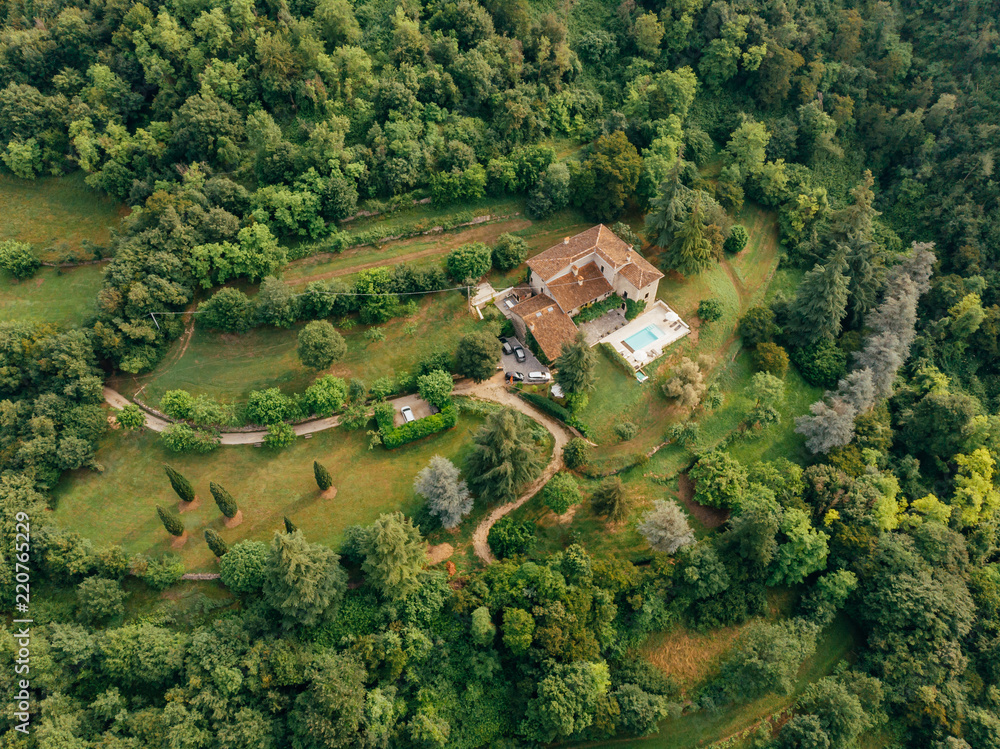 aerial view of villa with swimming pool between forest in Italy