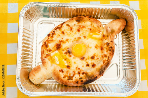 Khachapuri - traditional Georgian cheese and egg boat shaped pie in takeaway disposable box. Street and fast food concept