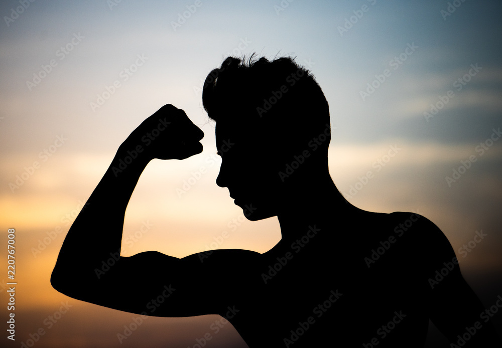 Strong athletic young guy. Beautiful silhouette against the setting sun.