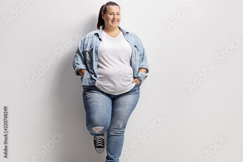 Young overweight woman standing against a wall photo