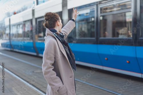 Schilderij op canvas Stylish woman waving at a passing tram