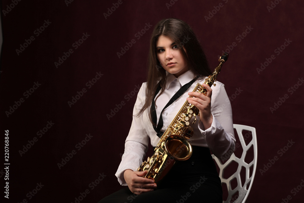 Naklejka premium Young girl with saxophone in studio on dark background