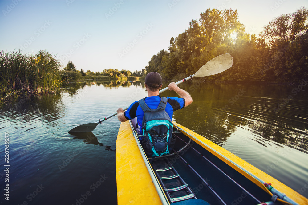 Rear view of kayaker man paddle kayak at sunset river. Rear view of kayaker man paddle kayak at sunset river.