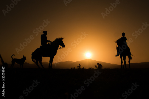 horses, cowboys, dogs at sunset