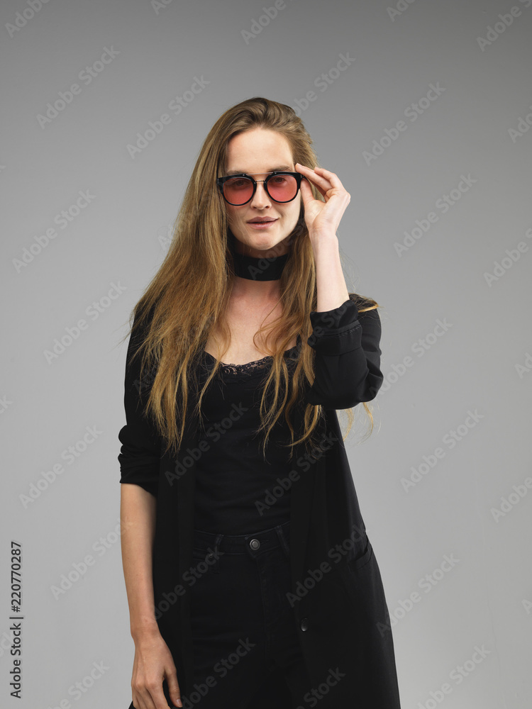 Want to see you clearly. Attractive model young woman raises the glasses with hand. Portrait shot in studio. Want to see you clearly. Attractive model young woman raises the glasses with hand. Portrait shot in studio.