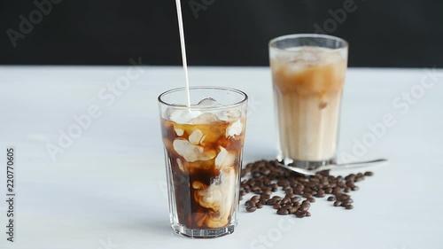 Concept of coffee and cocktails. Cream poured into coffee with ice