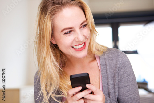 cheerful young blond woman holding cell phone