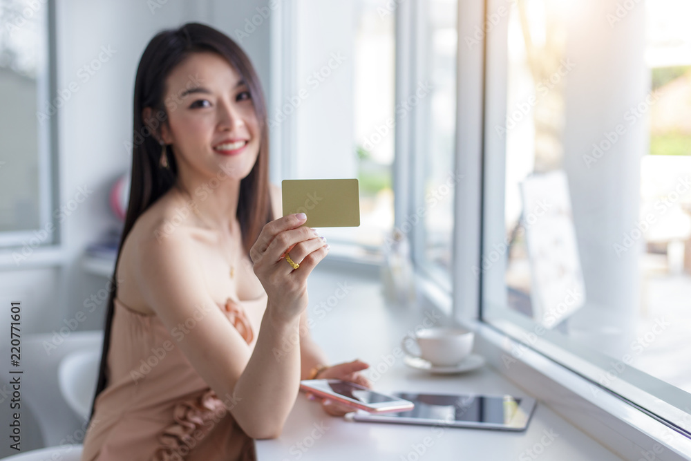 Young asian woman holding credit card and using tablet. Online shopping concept