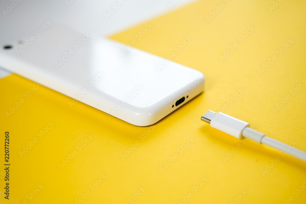 Fototapeta premium Smartphone Connects to Charger through Cable on Yellow Background. copy Space for insert text.