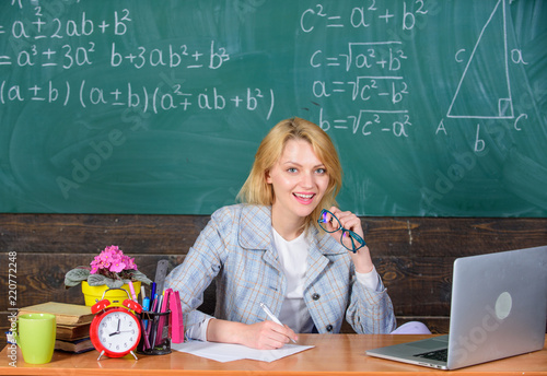 Teacher woman sit table chalkboard background. Excellent communicability and interpersonal skills. Organize class and make learning easy and meaningful process. Well organized and committed teacher photo