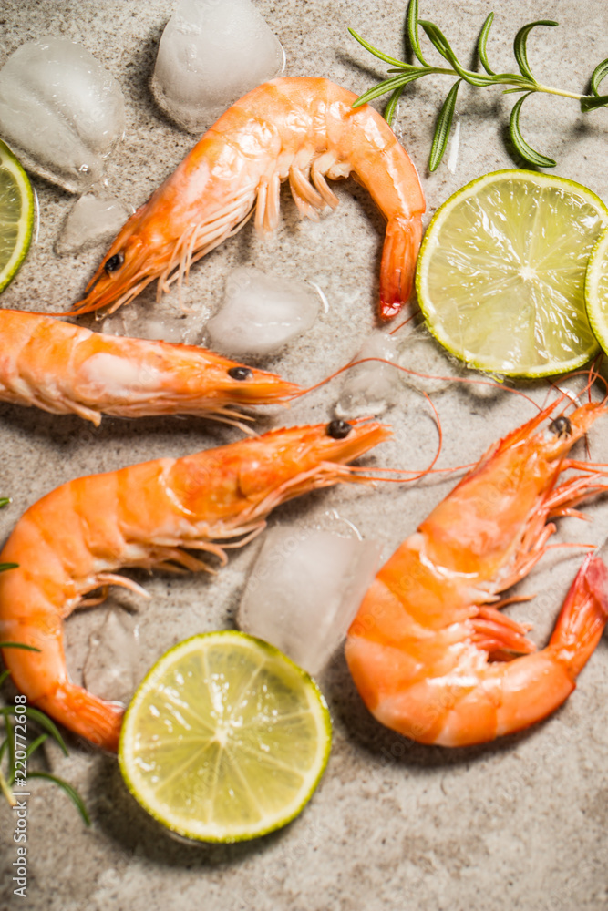 Tiger shrimps with lime, lemon, rosemary and black pepper spices on stone background. Fresh tasty prawns ready to be cooked. Tiger shrimps with lime, lemon, rosemary and black pepper spices on stone background. Fresh tasty prawns ready to be cooked.
