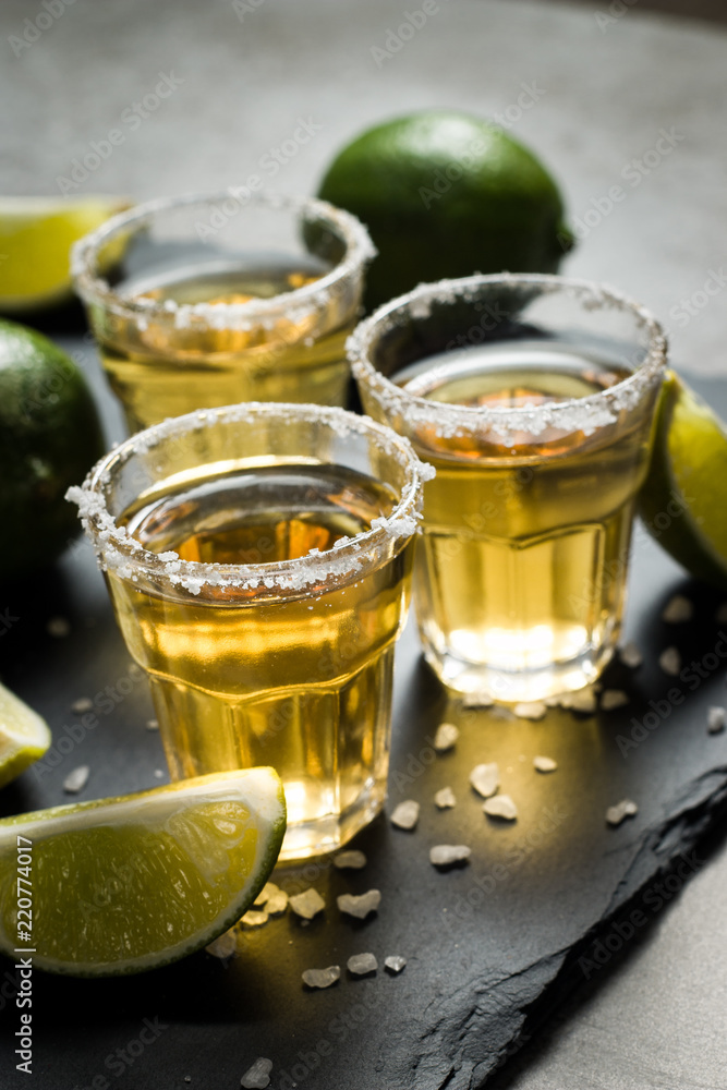 Macro photo of shots of gold Mexican tequila with lime and salt on wooden rustic background. Alcoholic drink concept. selective focus. Macro photo of shots of gold Mexican tequila with lime and salt on wooden rustic background. Alcoholic drink concept. selective focus.