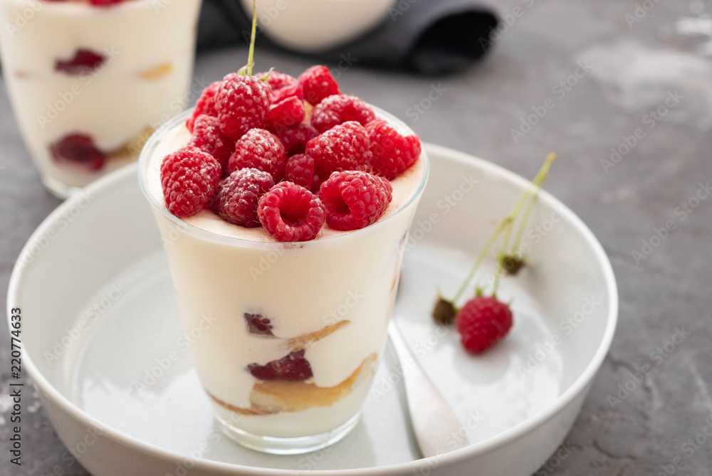 Tiramisu with raspberry in glasses on grey background. Italian dessert. Copy space. Tiramisu with raspberry in glasses on grey background. Italian dessert. Copy space.