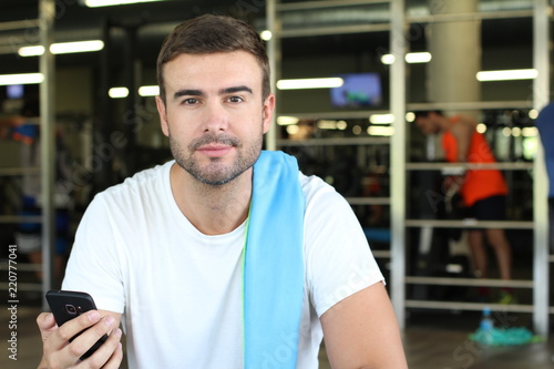 Handsome man holding cellphone at the gym