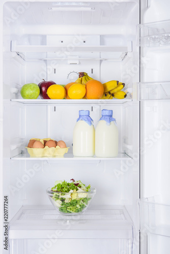 fruits, bottles of milk and salad in fridge