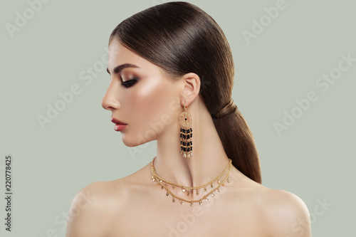 Elegant woman with makeup, straight hair and fashion jewelry. Perfect female face. Beauty and accessories.
