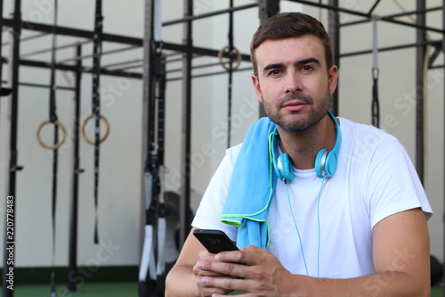 Handsome man holding cellphone at the gym