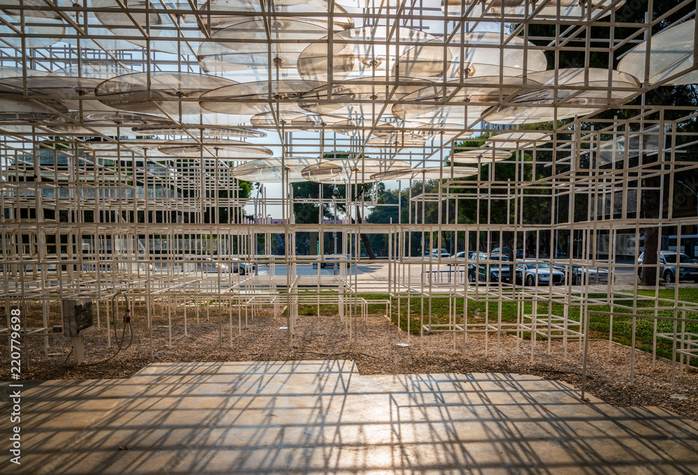 Abstract modern art steel framework giving shade in public park in Albania.