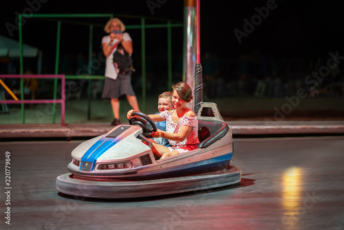 Young girl and boy driving a bumper car at a amusement park at night.