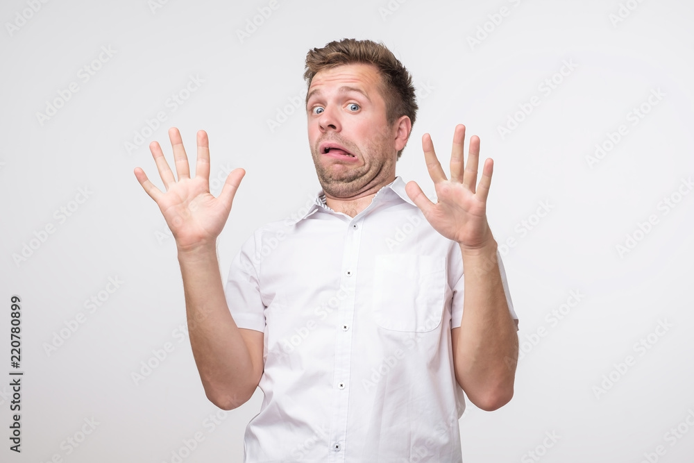 I am afraid concept. Portrait of young scared man in white shirt. Male halflength portrait