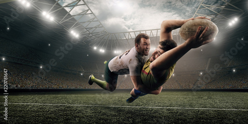 Two male Rugby players fight for the ball in flight on professional rugby stadium © Alex