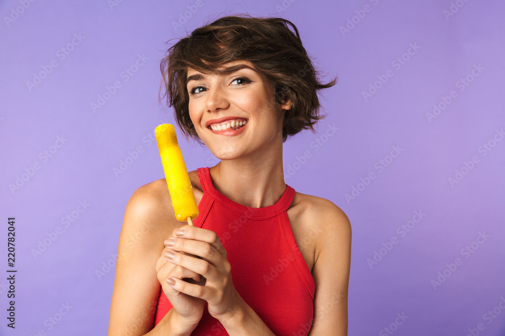 Image of glad brunette woman 20s in casual wear smiling and holding ice cream, isolated over violet background Image of glad brunette woman 20s in casual wear smiling and holding ice cream, isolated over violet background