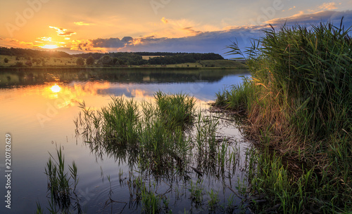 Sunset on the lake. The water reflects the setting sun and clouds. photo