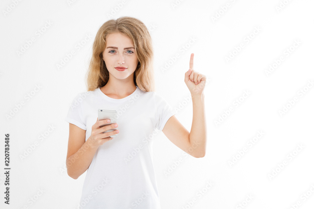Portrait of a smiling young girl pointing finger isolated on white background. Woman holding smartphone. Copy space.Blank Portrait of a smiling young girl pointing finger isolated on white background. Woman holding smartphone. Copy space.Blank