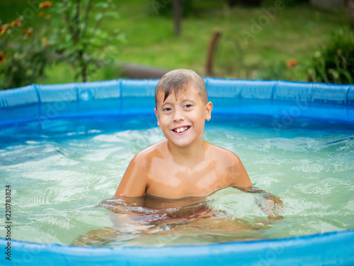 Cute blond boy bathing in a small pool