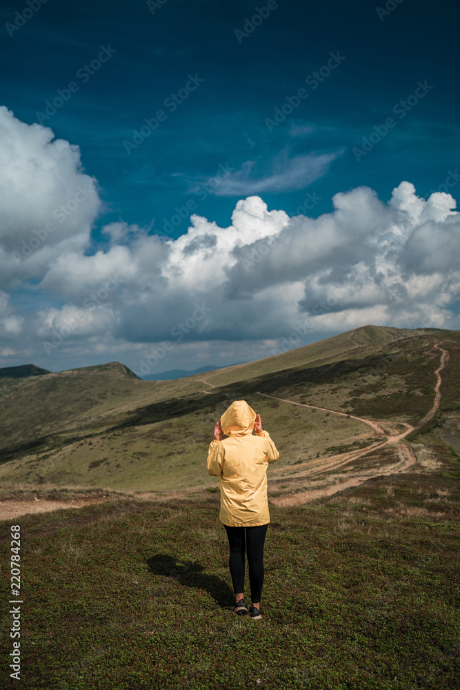 A young woman in a yellow raincoat on top of a mountain. Carpathians, Ukraine