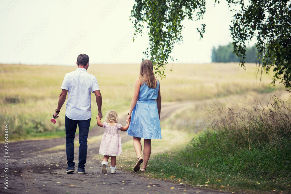 Family mother, father and little daughter beautiful and happy outdoors on the road in the field Family mother, father and little daughter beautiful and happy outdoors on the road in the field